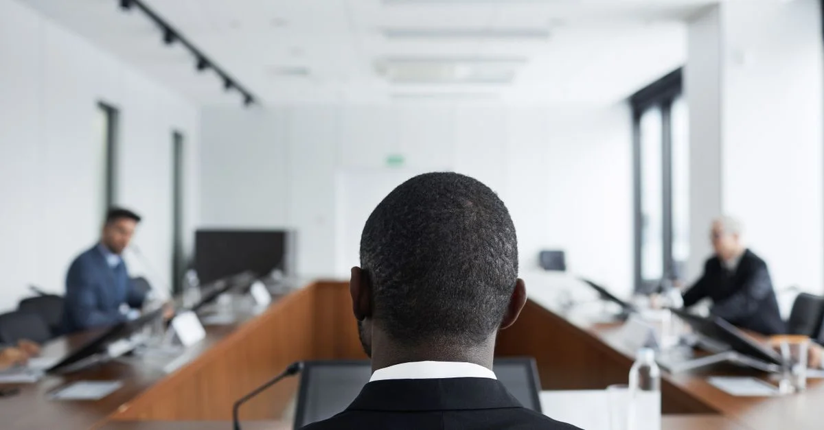 Vue arrière de professionnels lors d'une réunion d'affaires dans une salle de conférence lumineuse.