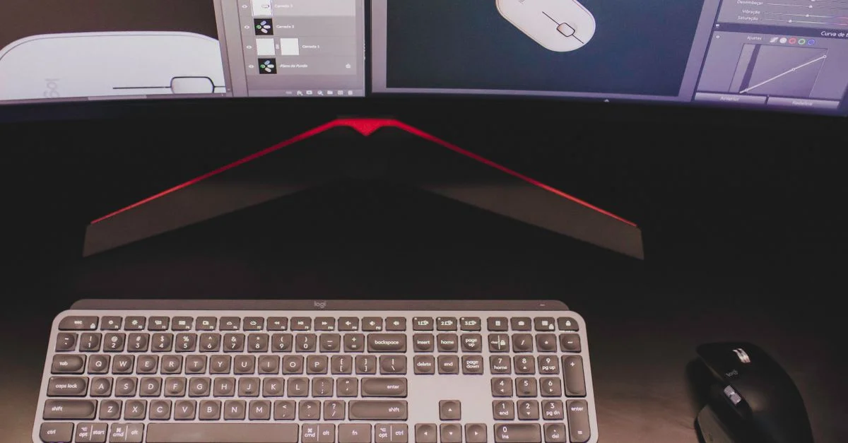 Gros plan d'un bureau élégant présentant un clavier et une souris avec deux écrans affichant un logiciel de design.