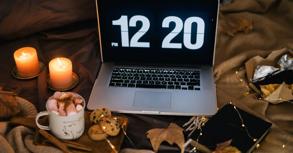 Un espace de travail confortable avec un ordinateur portable, des bougies et une tasse de chocolat chaud, parfait pour les soirées d'automne.