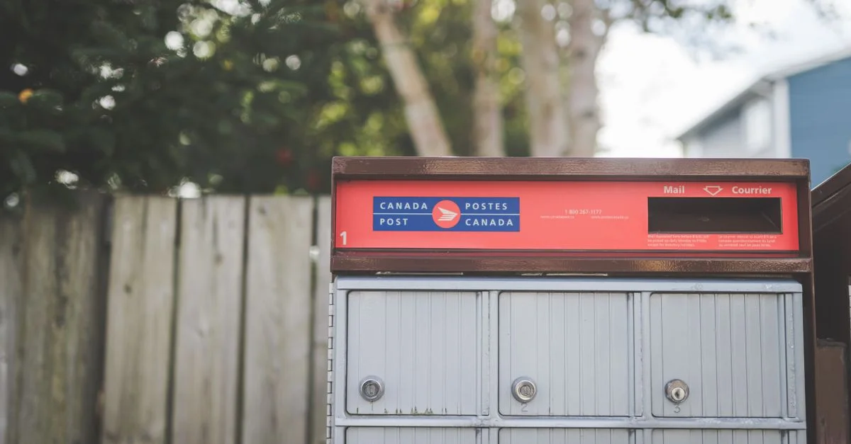 Gros plan d'une boîte aux lettres de Canada Post à l'extérieur avec un arrière-plan naturel.