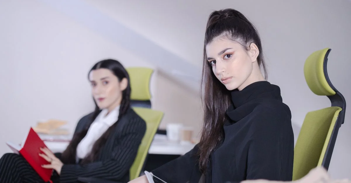 Deux femmes d'affaires assises dans un bureau moderne avec de la technologie, engagées dans leur travail.