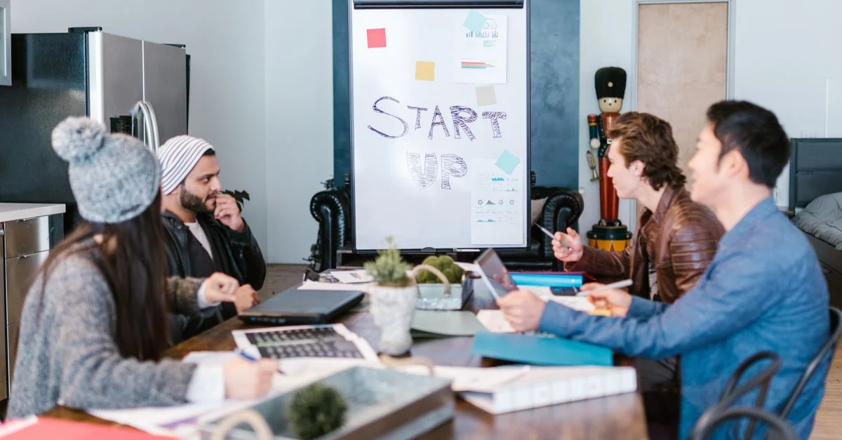 Un groupe diversifié d'adultes travaillant autour d'une table dans un bureau de startup, planifiant et discutant des idées.