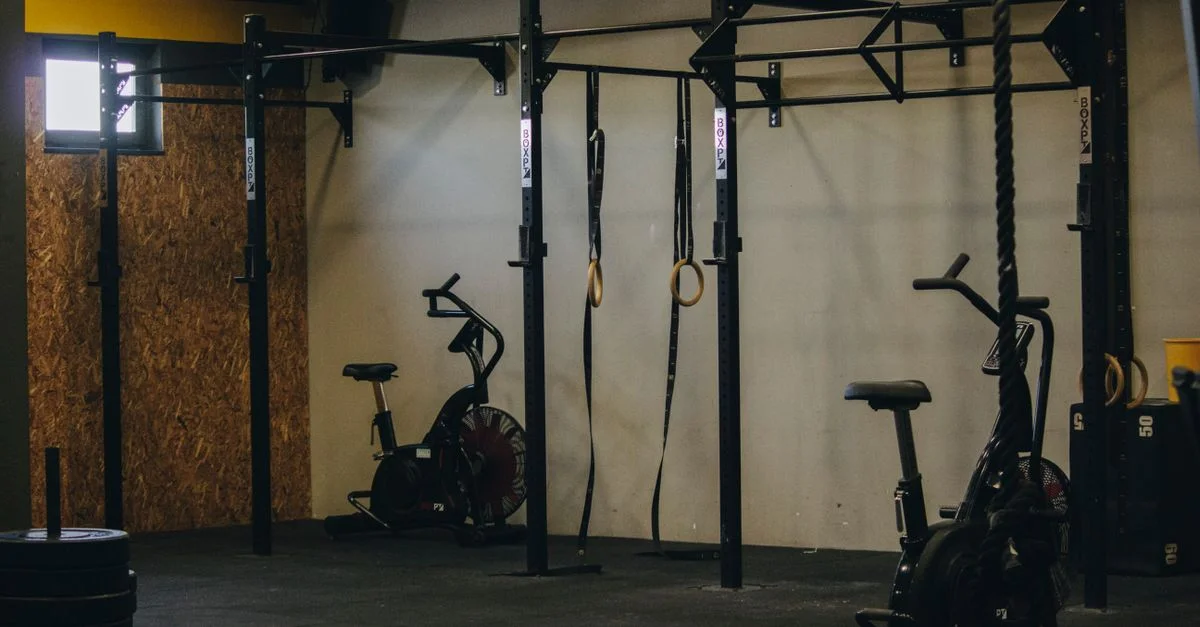 Salle de sport au style industriel avec des vélos d'exercice, des anneaux et des barres de traction en Angola.