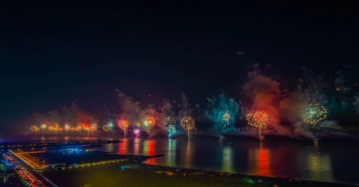 Vue aérienne spectaculaire de feux d'artifice colorés illuminant le front de mer de Ras Al-Khaimah la nuit.