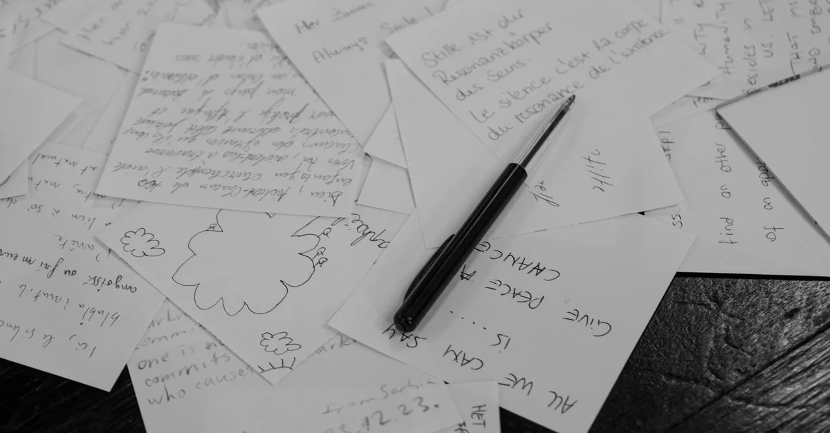 Une collection de notes manuscrites éparpillées sur un bureau avec un stylo en noir et blanc.