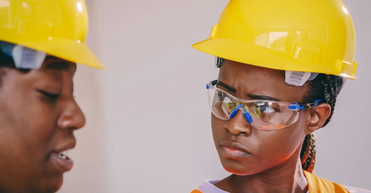 Gros plan sur des ouvriers de la construction afro-américains portant des équipements de sécurité, y compris des casques et des gilets.