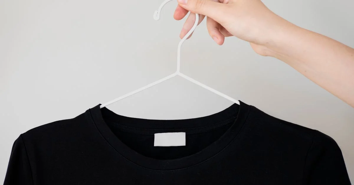 T-shirt noir sur cintre avec main tenant, idéal pour des maquettes de vêtements.
