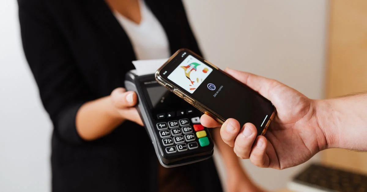 Une personne utilisant un smartphone pour un paiement sans contact au comptoir d'un magasin.