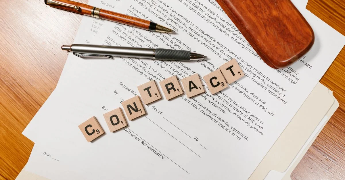 Gros plan sur des documents de contrat avec des carreaux de Scrabble épelant 'CONTRAT'.