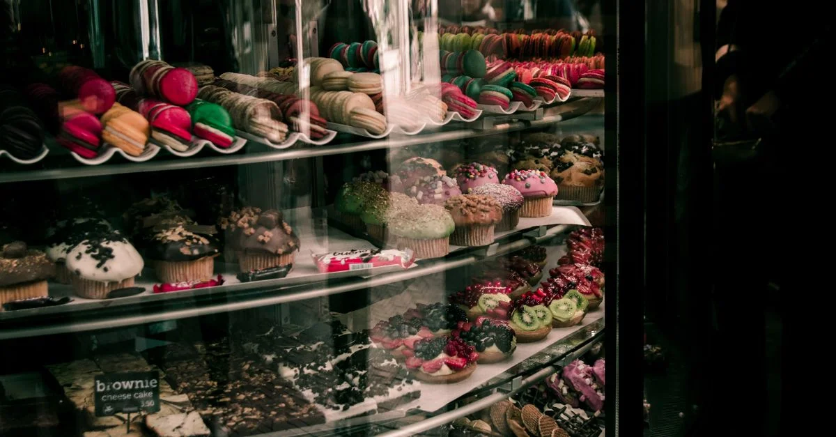 Un assortiment coloré de pâtisseries, macarons et cupcakes exposés dans une boulangerie à Bruxelles.