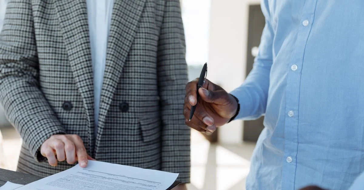 Deux professionnels examinant des documents d'affaires et discutant des détails dans un cadre de bureau.