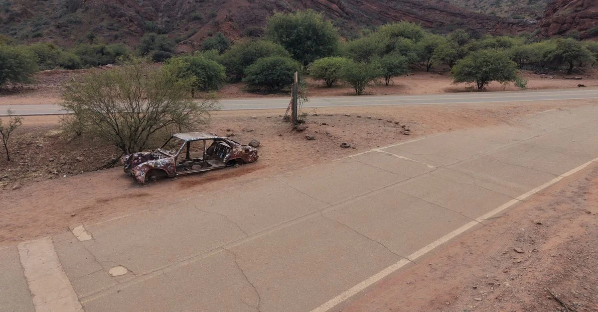 Une voiture abandonnée rouillée au bord de la route dans le terrain aride de Salta, Argentine.