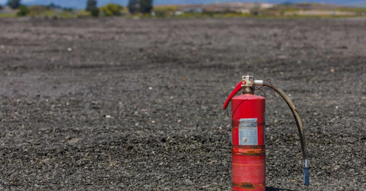 Un extincteur de feu rouillé solitaire se dresse sur un paysage stérile de gravier.