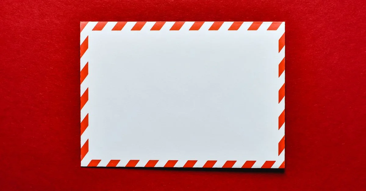 Une enveloppe blanche vide avec des rayures rouges sur un fond rouge vif, parfaite pour des thèmes postaux.