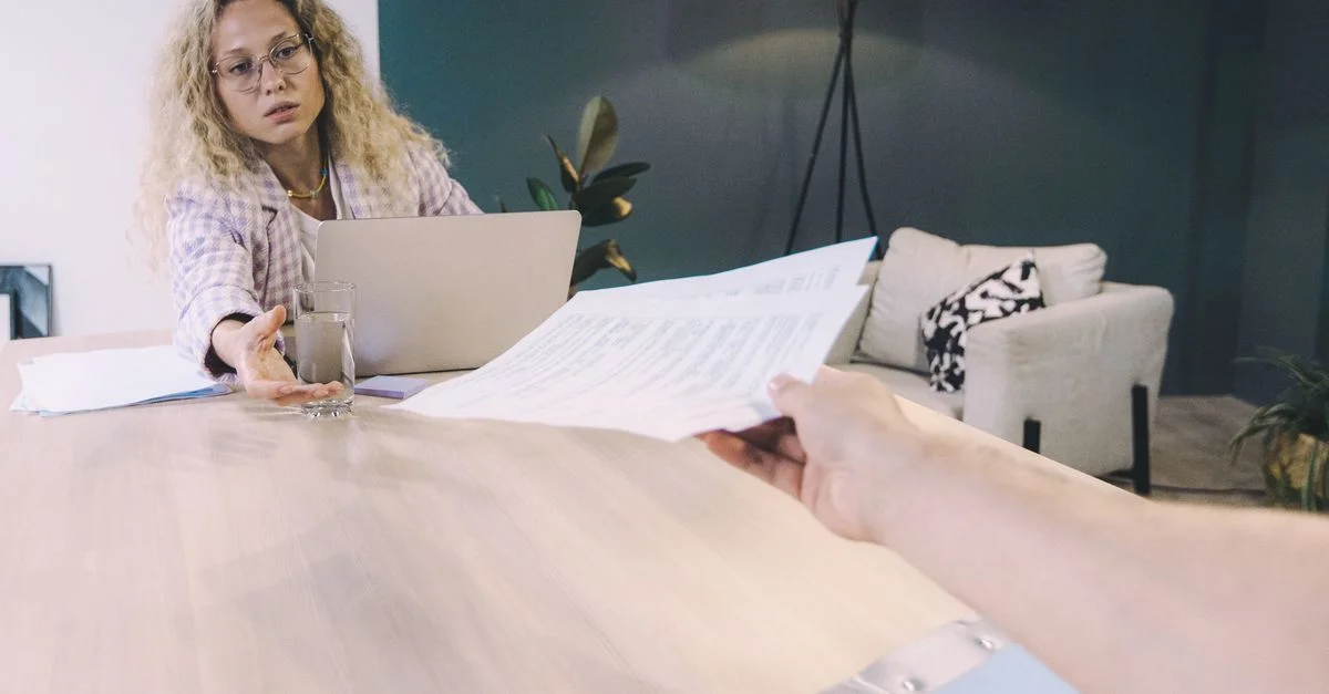 Femme professionnelle livrant des documents à travers une table dans un bureau contemporain.