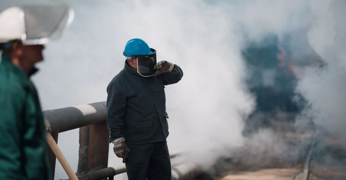 Des travailleurs industriels en tenue de protection entourés de lourde fumée, garantissant la sécurité dans des environnements difficiles.